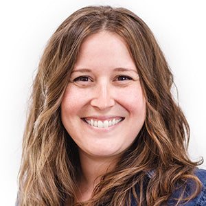 Person with long brown hair smiling against a plain background